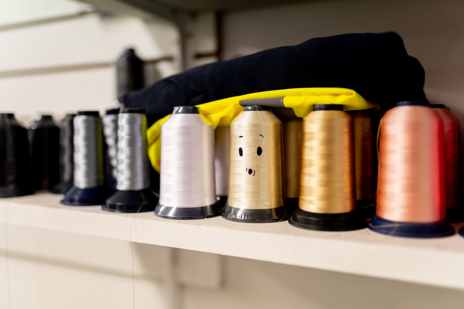 Thread rolls for use on an embroidery machine. One of the rolls has a smile on it's face.