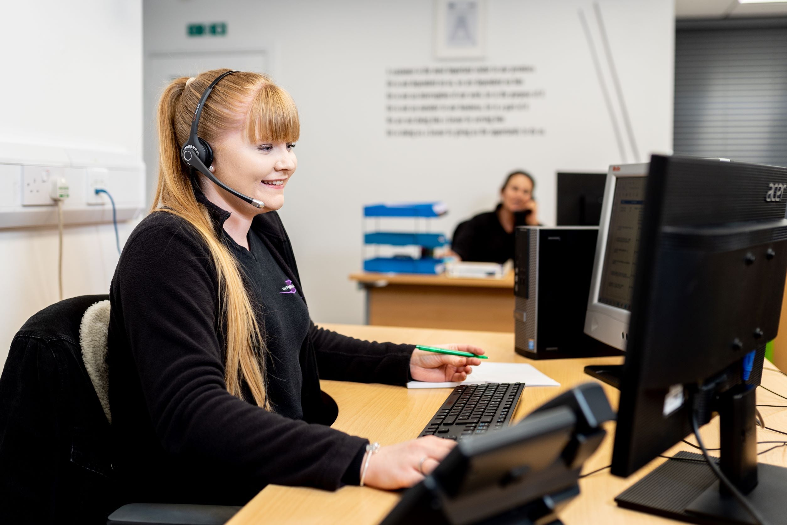 A lady using computer and a telephone headset  communicating by e-mail